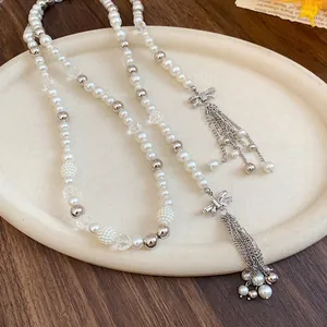 Detailed shot of long pearl necklace with rhinestone-encrusted bow and tassel charms