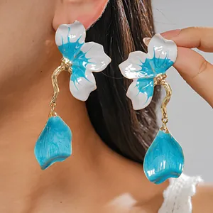 Detailed view of Western resort style blue and white enamel floral drop earrings on model