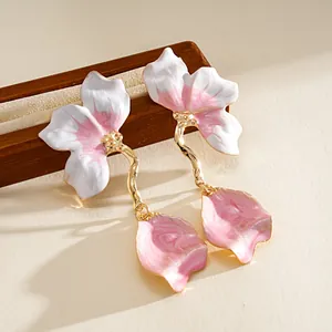 Close-up detail of pink and white enamel flower drop earrings with gold-tone stems