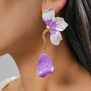 Close-up detail showing a vibrant purple and white enamel flower earring on a model ear.