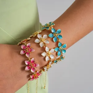 Close-up of elegant gold-tone bracelets featuring vibrant enamel flower charms