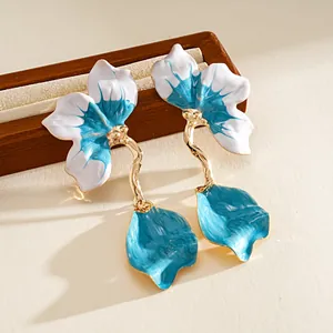 Detailed macro view of blue and white enamel flower petals on golden earrings