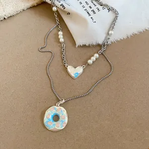 Vue détaillée du collier avec pendentif beignet et cœur Lucky avec perles sur tissu