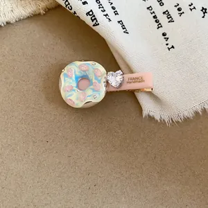 Gros plan d'une pince à cheveux donut de style crème avec un cristal en cœur