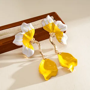 Detailed close-up of yellow and white enamel flower earrings with gold drop petals.