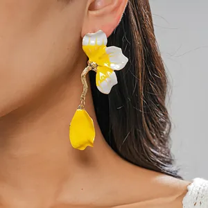 Close-up detail of yellow and white floral enamel stud earrings on model's ear