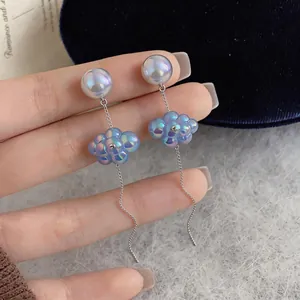 Dettaglio di orecchini a nappa a nuvola blu iridescente con perle e catenine d'argento