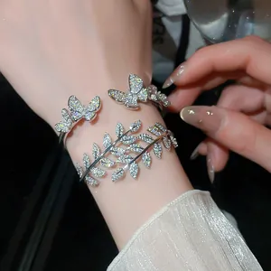 Detailed macro shot of shimmering zircon butterfly and leaf cuff bracelets on wrist