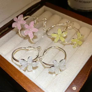 Primer plano de pendientes de aro plateados con colgantes de flores de resina de colores.