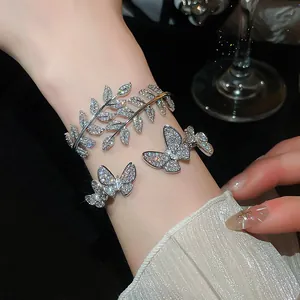 Close-up detail of a sparkly cubic zirconia leaf bracelet and butterfly ring set on a wrist.