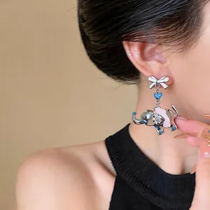 Detailed close-up view of a silver bow and elephant earring with blue heart zircon