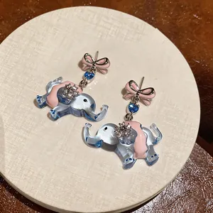 Detail view showing cartoon elephant earrings with pink bow and blue translucent finish