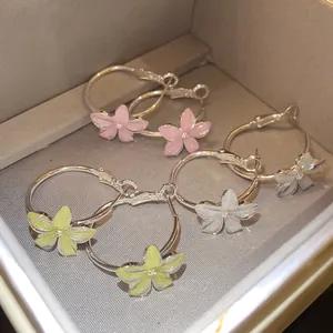Detalle de set de pendientes de aro con flores de resina en rosa, amarillo y blanco.