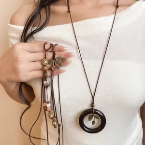 Détail d'un long collier ethnique fait main avec graines de Bodhi et pendentif en bois