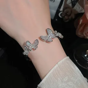 Detail view of a silver-tone cuff bracelet featuring crystal-encrusted butterflies.