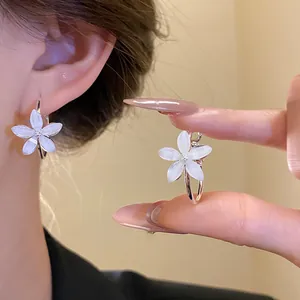 Primer plano detallado de pendientes de aro con flores de resina blanca y diseño
