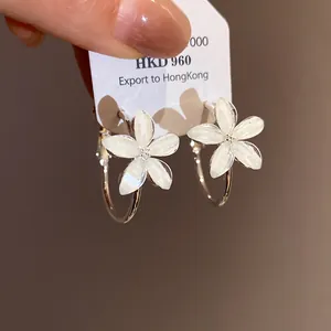 Vista detallada de los pendientes de aro con flores de resina y pétalos blancos