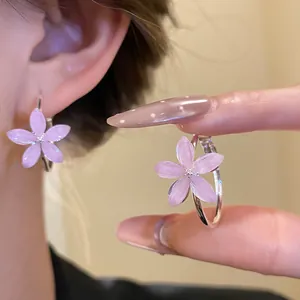 Vista de primer plano de pendientes de aro con flores de resina rosa y pétalos brillantes suaves