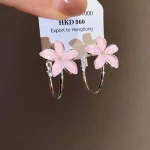 Detalle de elegantes pendientes de aro con flores de resina rosa y agujas de plata