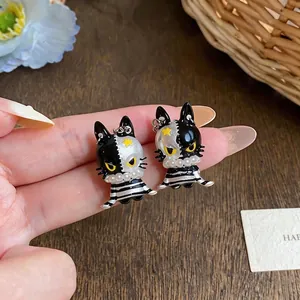 Exquisite asymmetric black and white enamel cat stud earrings with elegant pearl details