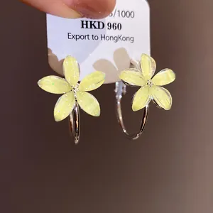 Detalle de pendientes de aro con flores de resina amarilla con purpurina y agujas de plata