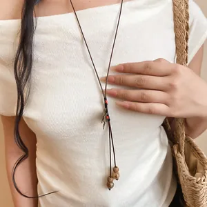 Gros plan d'un long collier de style ethnique avec corde tissée main et graines de Bodhi