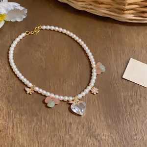 Elegant pearl necklace with zircon heart and butterfly pendants on wooden background