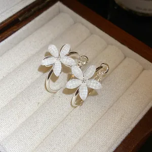 Detalle macro de pendientes de flores de resina blanca con agujas de plata en caja