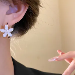 Primer plano de pendientes de aro con flores de resina y aguja de plata puestos