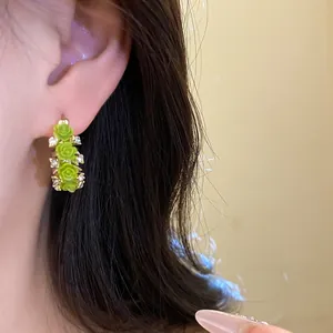 Detailansicht von grünen Blumenohrringen aus Harz mit Strass am Ohr des Modells