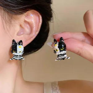 Detail view of asymmetrical black and white cat earrings with tiny pearl necklaces
