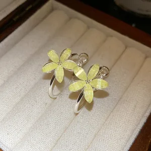 Primer plano de pendientes de aro con flores de resina amarilla con purpurina en caja