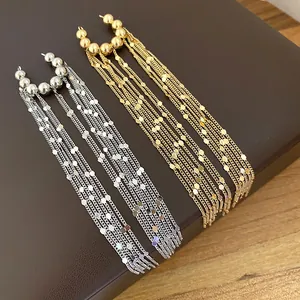 Detailansicht langer Quasten-Ohrclips in Gold und Silber mit Scheibenakzenten.
