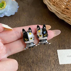 Detailed view of asymmetric enamel cat earrings with pearl and star accents