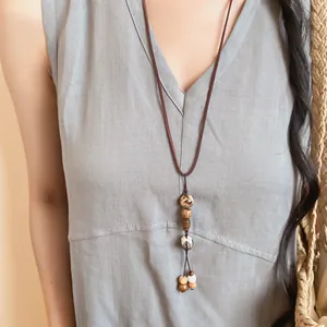 Détail d'un collier artisanal en graines de Bodhi de style néo-chinois porté sur une robe
