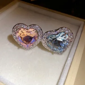 Elegant heart-shaped zircon rings in pink and blue with sparkly diamond accents in a box