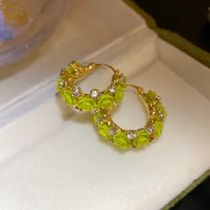 Detailansicht goldener Creolen mit grünen Harzrosen und funkelnden Strasssteinen