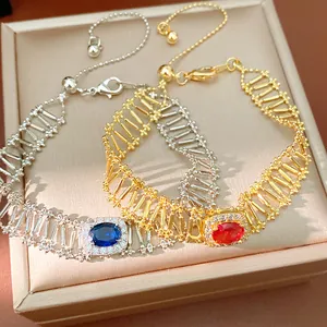 Primer plano de pulseras huecas de oro y plata con piedras ovaladas azules y rojas