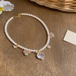Elegant pearl necklace featuring zircon heart and butterfly pendants on wood background