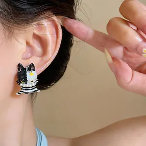 Detailed close-up view of a black and white cartoon cat stud earring with pearls on the ear