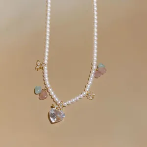 Detailed close-up of a pearl necklace with heart zircon and butterfly charms