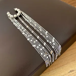 Detailansicht eleganter silberner langer Quasten-Ohrclips mit hängenden Ketten und Perlen.