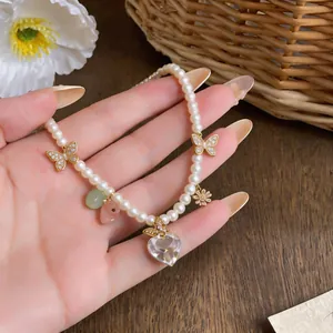 Detailed macro view of elegant pearl necklace with zircon heart and butterfly charms.