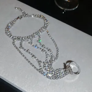 Elegante pulsera de mano con pedrería plateada y detalle de anillo ajustable para mujer