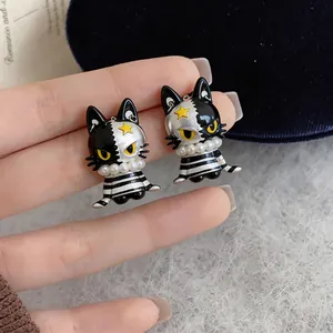 Detailed view of asymmetrical black and white cat stud earrings with pearl collar detail