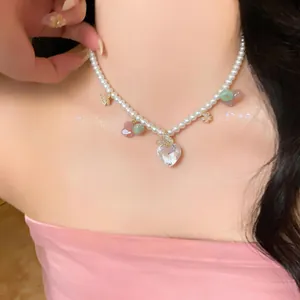 Close-up detail of a pearl necklace with heart-shaped zircon and butterfly charms worn on a neck.
