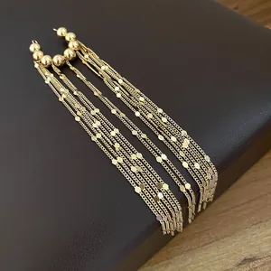 Detaillierte Nahaufnahme goldener langer Quasten-Ohrklemmen mit feinen Ketten und Scheiben.