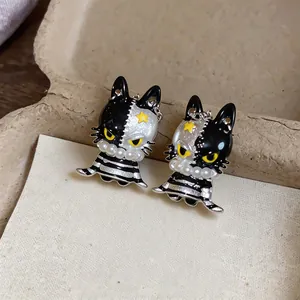 Macro detail of asymmetrical cat stud earrings with enamel finish and small pearl collars