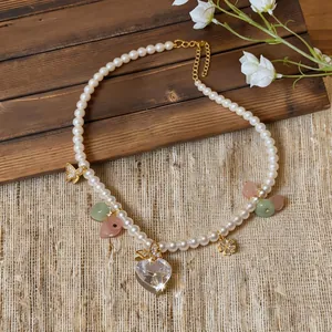 Close-up of pearl necklace with crystal heart pendant and golden butterfly charms