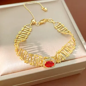 Primer plano de una pulsera dorada con piedra de circón rojo en caja de satén